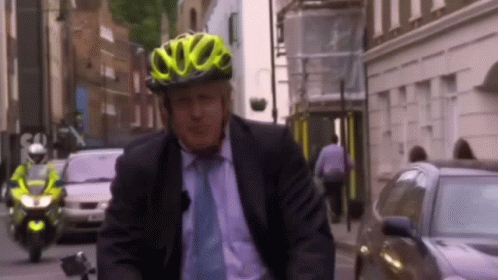 A Man Wearing A Yellow Helmet Is Riding A Bike GIF