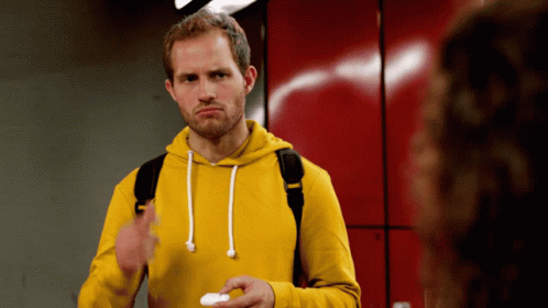 A Man Wearing A Yellow Hoodie Is Holding A White Object GIF