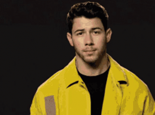 A Man Wearing A Yellow Jacket And A Black Shirt Looks At The Camera GIF