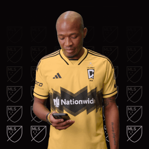 A Man Wearing A Yellow Jersey That Says Nationwide Looks At His Phone GIF