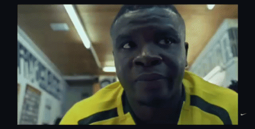 A Man Wearing A Yellow Nike Shirt Is Looking At The Camera GIF