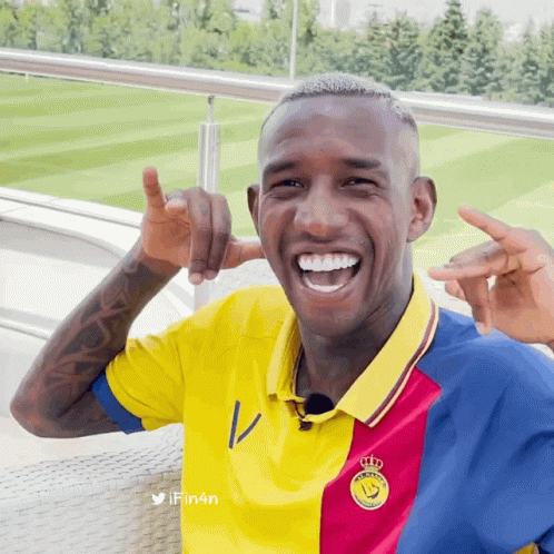 A Man Wearing A Yellow Red And Blue Shirt With A Crown On The Front GIF