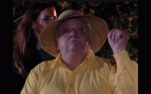 A Man Wearing A Yellow Shirt And A Straw Hat Is Being Kissed By A Woman GIF