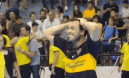 A Man Wearing A Yellow Shirt That Says Uruguay On It Is Holding His Head . GIF