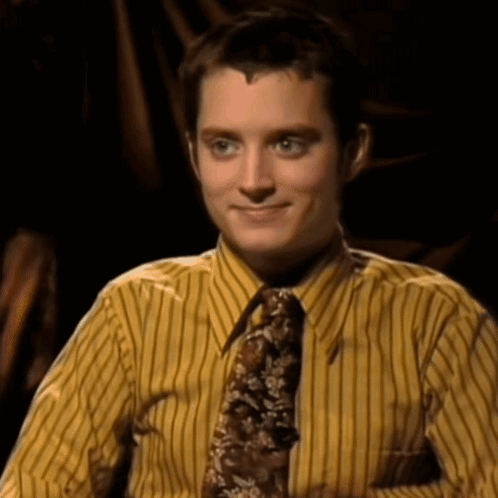 A Man Wearing A Yellow Striped Shirt And Tie Smiles For The Camera GIF