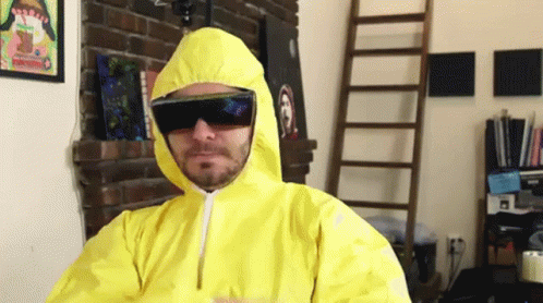 A Man Wearing A Yellow Suit And Sunglasses Is Standing In Front Of A Fireplace GIF