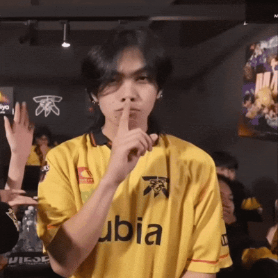 a man wearing a yellow ubia shirt holds his finger to his lips