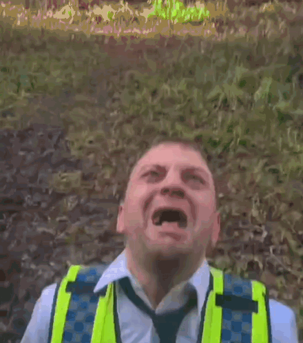 A Man Wearing A Yellow Vest And Tie Is Making A Face GIF