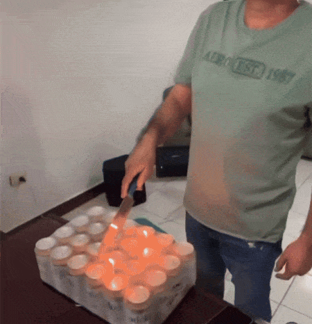 A Man Wearing An Aeropostale Shirt Is Cutting A Bunch Of Candles With A Knife GIF