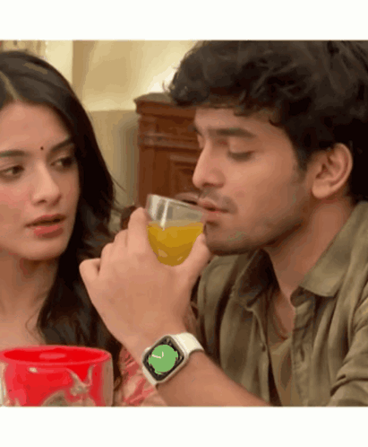 A Man Wearing An Apple Watch Is Drinking Orange Juice Next To A Woman GIF
