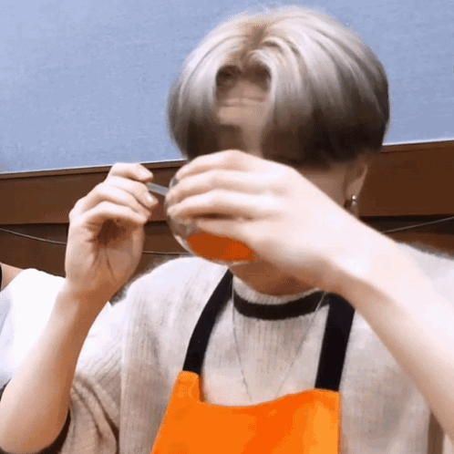 A Man Wearing An Apron Is Drinking From A Cup GIF