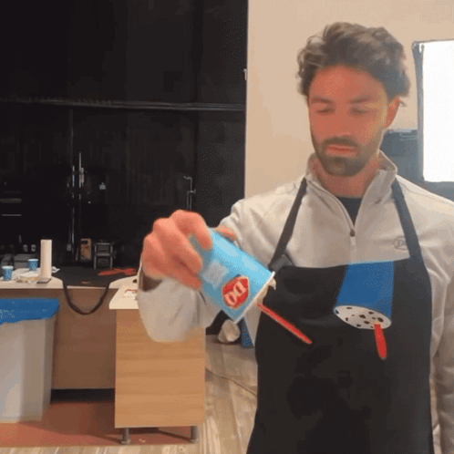 A Man Wearing An Apron Is Pouring A Drink Into A Cup That Says Dq On It GIF
