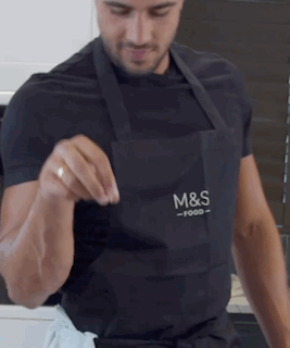 A Man Wearing An Apron That Says M & S Food On It GIF