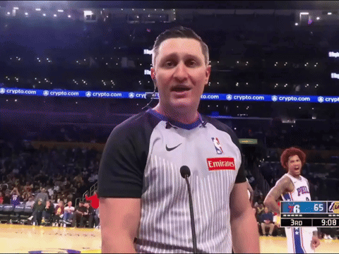 a man wearing an emirates shirt stands in front of a microphone on a basketball court