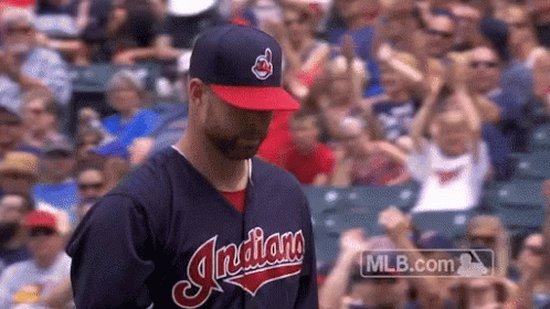 A Man Wearing An Indians Baseball Uniform Stands In Front Of A Crowd GIF