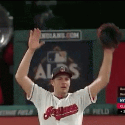 A Man Wearing An Indians Jersey Is Raising His Hands In The Air GIF