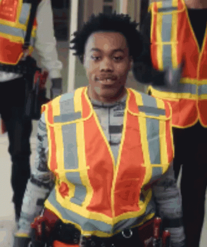 a man wearing an orange and yellow safety vest with the letter t on it