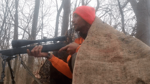 A Man Wearing An Orange Hat Is Holding A Rifle GIF