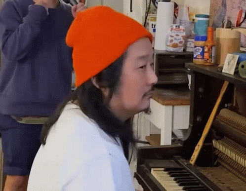 A Man Wearing An Orange Hat Is Playing The Piano GIF