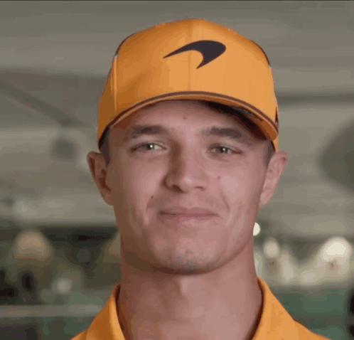 A Man Wearing An Orange Hat With A Mclaren Logo GIF