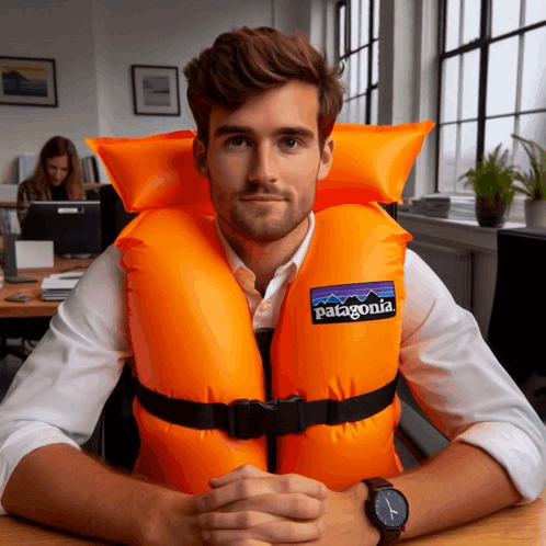 A Man Wearing An Orange Life Vest That Says Patagonia On It GIF