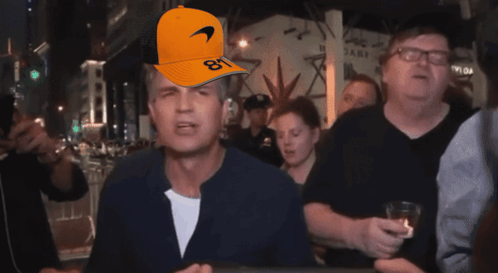 A Man Wearing An Orange Mclaren Hat With The Number 81 On It GIF