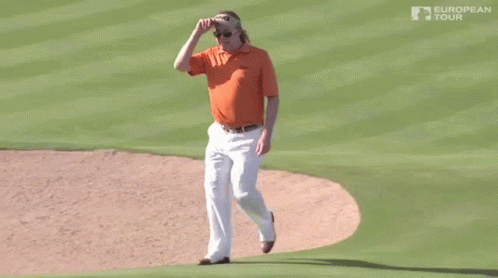 A Man Wearing An Orange Shirt And White Pants Is Walking On A Golf Course Sponsored By The European Tour GIF