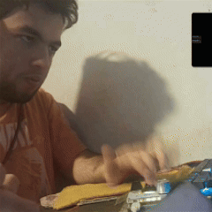 A Man Wearing An Orange Shirt That Says ' Real ' On The Front GIF