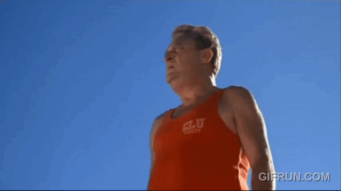 A Man Wearing An Orange Tank Top That Says C.l.u. On It GIF