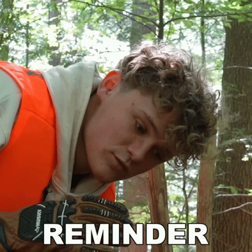A Man Wearing An Orange Vest And Husky Gloves Is Looking At Something In The Woods GIF