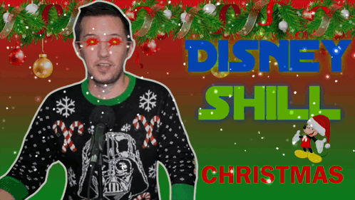 A Man Wearing An Ugly Christmas Sweater Stands In Front Of A Microphone With The Words Disney Still Christmas Behind Him GIF