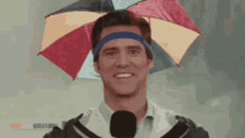 A Man Wearing An Umbrella On His Head With A Microphone GIF