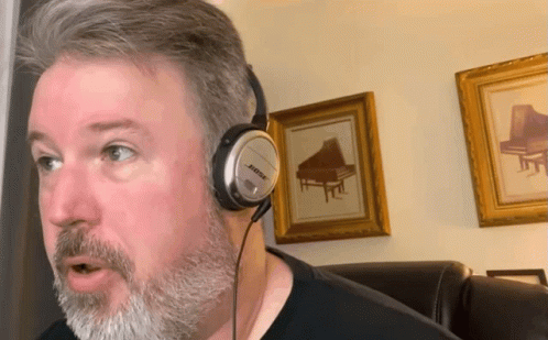 A Man Wearing Bose Headphones Is Talking GIF