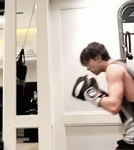 A Man Wearing Boxing Gloves Is Standing In Front Of A Mirror GIF