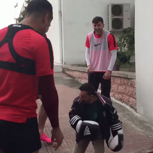 A Man Wearing Boxing Gloves That Say Adidas Is Standing Next To Another Man GIF