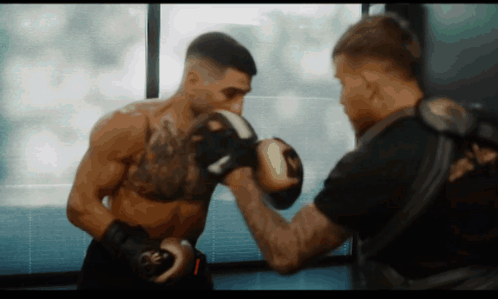 A Man Wearing Boxing Gloves With The Letter R On Them GIF