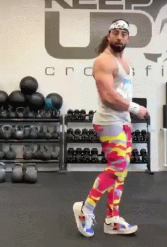 A Man Wearing Colorful Pants Is Standing In A Gym . GIF