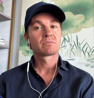 A Man Wearing Ear Buds And A Baseball Cap Looks At The Camera GIF