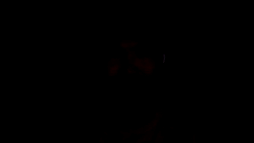 A Man Wearing Ear Buds Is Looking At The Camera In The Dark GIF