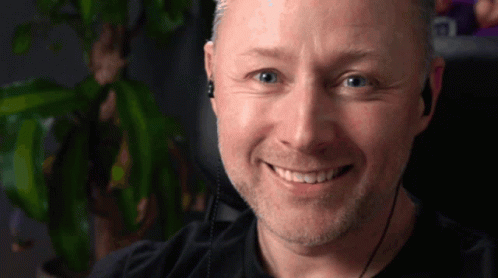 A Man Wearing Ear Buds Is Smiling For The Camera GIF