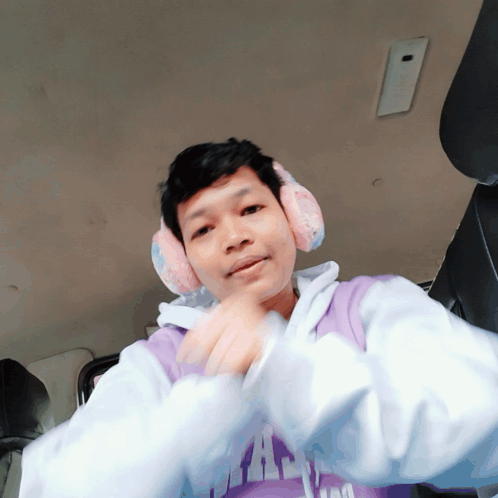 A Man Wearing Ear Muffs And A Purple Shirt That Says ' I Am ' On It GIF