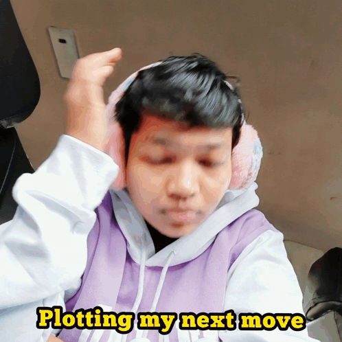 A Man Wearing Ear Muffs And A Purple Sweatshirt Says Plotting My Next Move GIF