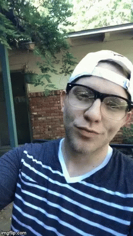 A Man Wearing Glasses A Hat And A Striped Shirt Takes A Selfie GIF