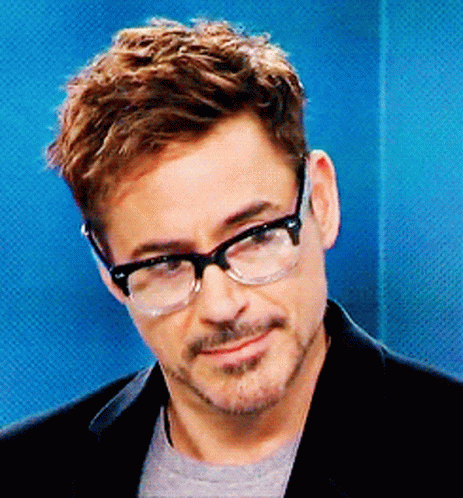 A Man Wearing Glasses And A Black Jacket Is Smiling GIF