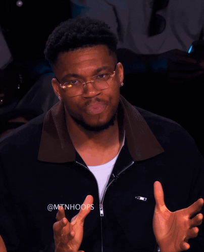 A Man Wearing Glasses And A Black Jacket With The Hashtag @Mtnhoops On It GIF