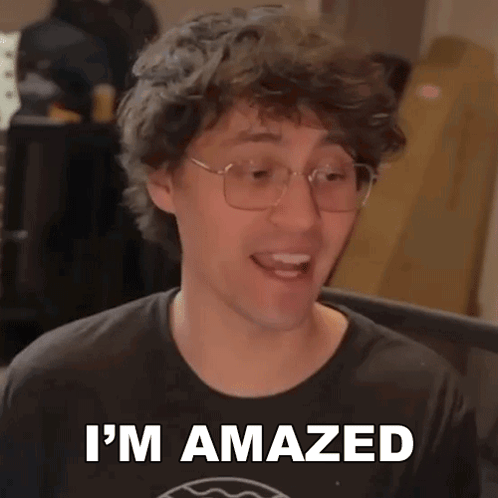 A Man Wearing Glasses And A Black Shirt Is Making A Funny Face And Saying I 'M Amazed . GIF