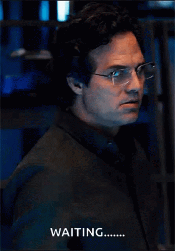 A Man Wearing Glasses And A Black Shirt Says Waiting GIF