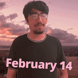 A Man Wearing Glasses And A Black Shirt With The Date February 14 On It GIF