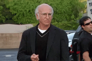 A Man Wearing Glasses And A Black Suit Is Standing In Front Of A Sign That Says ' The ' On It GIF