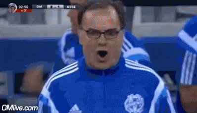 A Man Wearing Glasses And A Blue And White Adidas Shirt Is Shouting . GIF